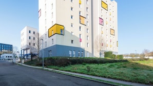 Un edificio residencial de varios pisos, con balcones, techo plano y cielo despejado.