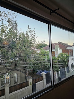 Paesaggio visibile da una finestra, con alberi e edifici sullo sfondo.