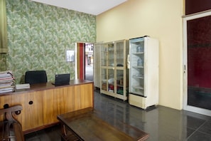 A reception area with a wooden desk, a laptop, a filing cabinet, and a glass-fronted storage unit. - Hotel O near Stadion Pahoman formerly Ra (Bandar Lampung)