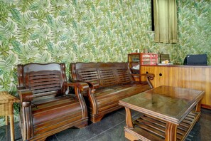 A room with a sofa set, a glass-top table, and a wooden cabinet. - Hotel O near Stadion Pahoman formerly Ra (Bandar Lampung)