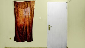 Ein Zimmer mit einer weißen Tür, einem gemusterten Vorhang und einem Bett.