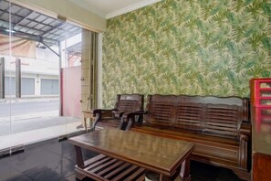 A room with a wooden bench, a table, and a patterned wallpaper. - Hotel O near Stadion Pahoman formerly Ra (Bandar Lampung)