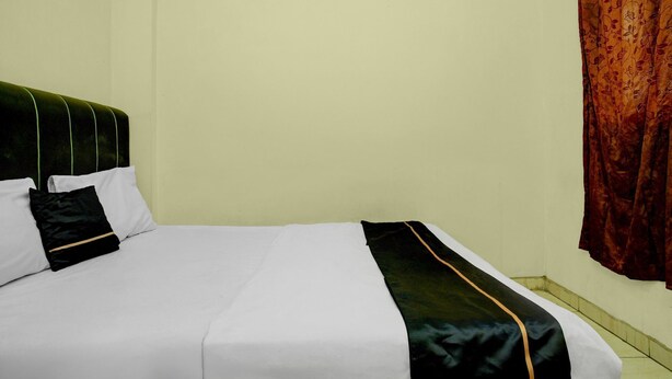 Ein Bett mit weißer Bettwäsche und schwarzen und goldenen Akzenten.