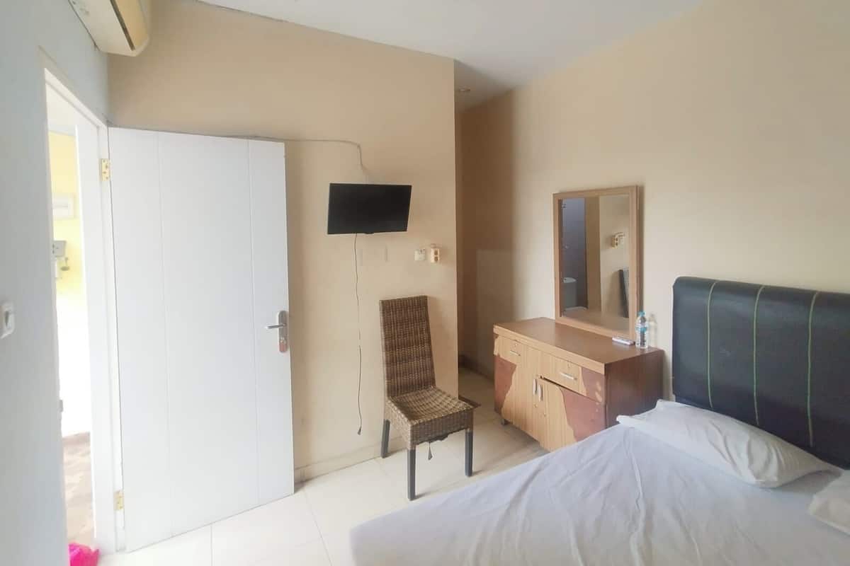 Una habitación de hotel con una cama, un escritorio, una silla, un televisor y un espejo.