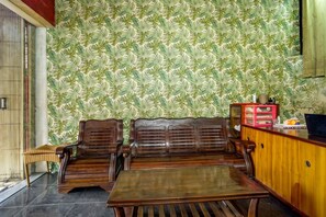 Um quarto com papel de parede estampado, móveis de madeira e um armário com gavetas.