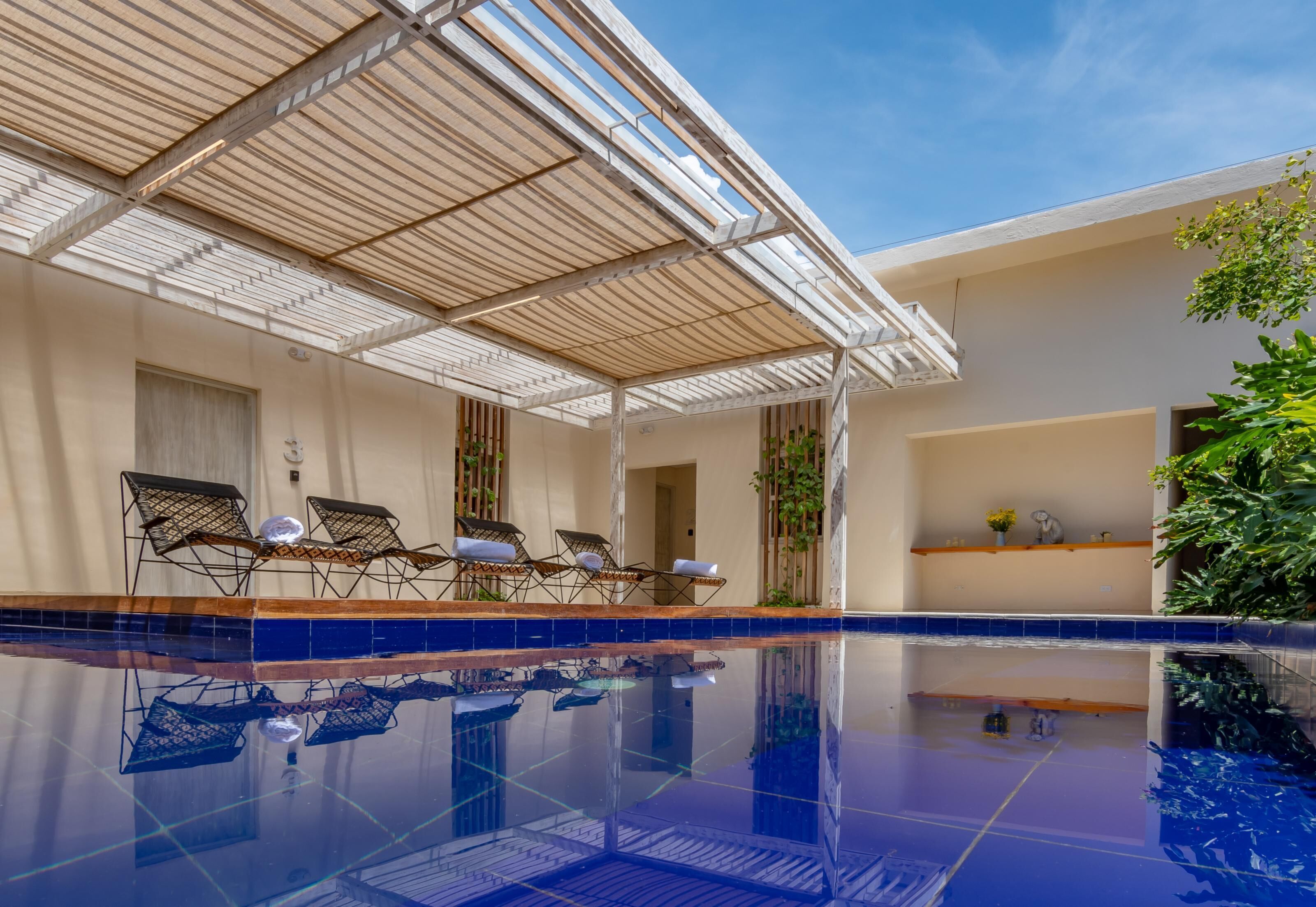 Un espace piscine avec des chaises longues et un coin salon abrité.
