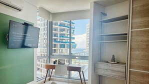 Et moderne hotelværelse med et stort vindue, et skrivebord, en stol, en seng og et klædeskab.