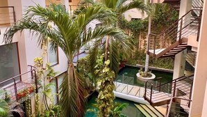 Un atrio interior de varios niveles con una fuente central, rodeado de abundante vegetación y varios balcones.