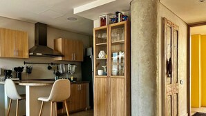 Una cocina moderna con armarios de madera, un comedor con una silla blanca y un mueble de madera grande con puertas de vidrio.