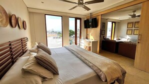 Una habitación de hotel con cama, escritorio, televisión y balcón con vistas.