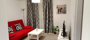 A living room with a red sofa, white coffee table, and a television on a stand. - Marousi Accomodation 2 bedrooms (Marousi)