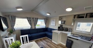 Ein kompaktes Wohnmobil-Interieur mit Sofa, Küchenzeile und Fenster mit Blick auf eine Wohngegend.