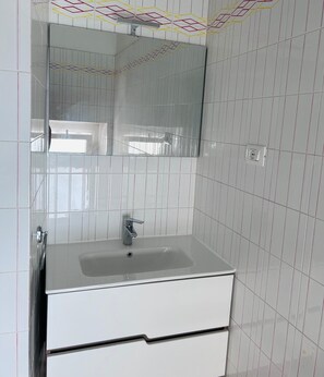 A bathroom with a white sink, a mirror, and a tiled wall. - Piazza Condo   Suite with Balcony (ACQUASPARTA)