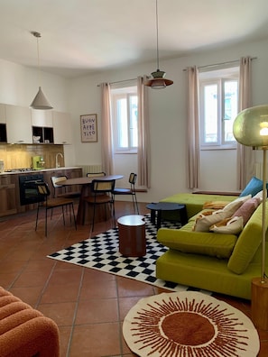 Ein moderner Wohnraum mit Küche, Essbereich und einem grünen Sofa.