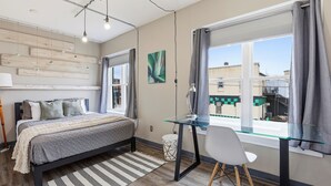 Ein modernes Schlafzimmer mit Bett, Schreibtisch und Fenster.