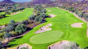 Ein Golfplatz mit gepflegten Fairways, Sandbunkern und umliegender Vegetation.