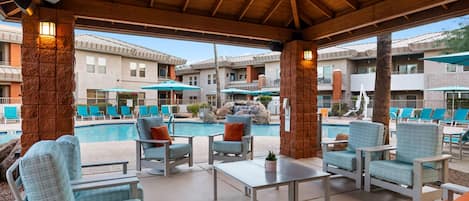 A poolside area with lounge chairs, umbrellas, and a pool.