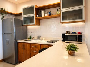 A modern kitchen with a stainless steel refrigerator, a built-in microwave, and wooden cabinets. - Beachfront Top Floor + Balcony | Teak Design (Bejuco)