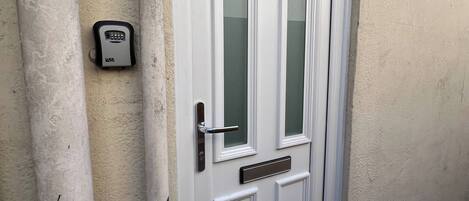 Una puerta blanca con cerradura electrónica, buzón de correo y ranura para correspondencia.