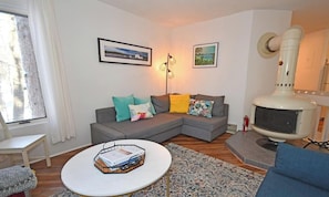 Ein Wohnzimmer mit einer Couch, einem Couchtisch, einem Kamin und zwei gerahmten Bildern an der Wand.