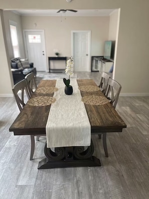 A dining table with a runner, chairs, and a vase of flowers.