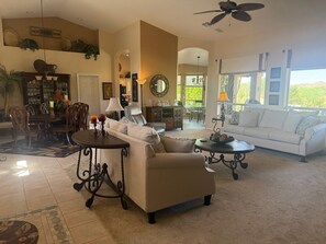 Ein geräumiges Wohnzimmer mit Essbereich, einer Couch, einem Couchtisch und einem Deckenventilator.