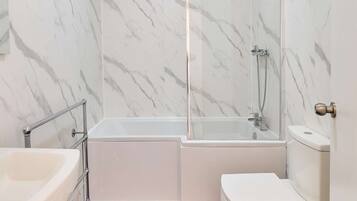 A bathroom with a glass-enclosed shower, a bathtub, and a toilet.