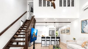 Een modern interieur met een houten trap, een keukenhoek en een woonkamer met een bank.