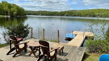 A wooden deck with a table and chairs overlooking a lake.