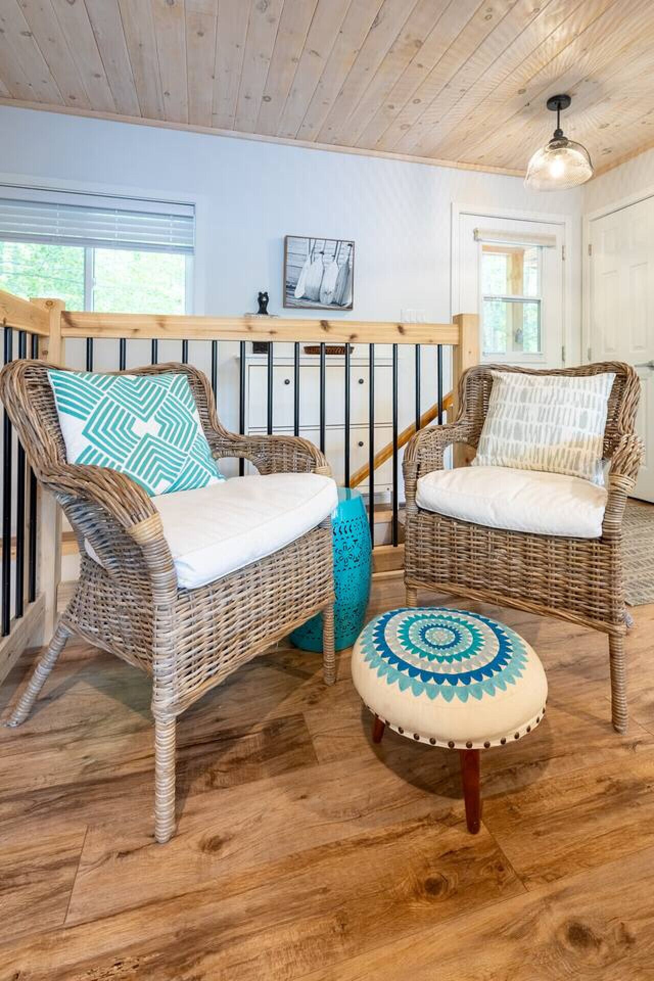 Wicker chairs with cushions, a wooden floor, a staircase, and a ceiling light fixture.