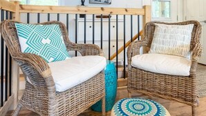 Wicker chairs with cushions, a wooden floor, a staircase, and a ceiling light fixture. - Diamond Lakehouse | SUP, Canoe, BBQ, Aurora Magic (Highland Grove)