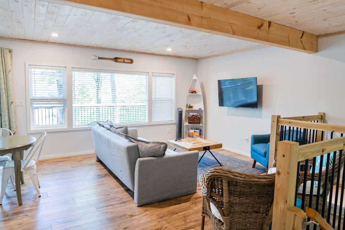 Un salon avec un canapé, une table, un téléviseur et une pancarte sur laquelle on peut lire « MAISON AU BORD DU LAC ».