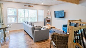 A living room with a sofa, a table, a TV, and a sign that reads 'LAKE HOUSE'. - Diamond Lakehouse | SUP, Canoe, BBQ, Aurora Magic (Highland Grove)