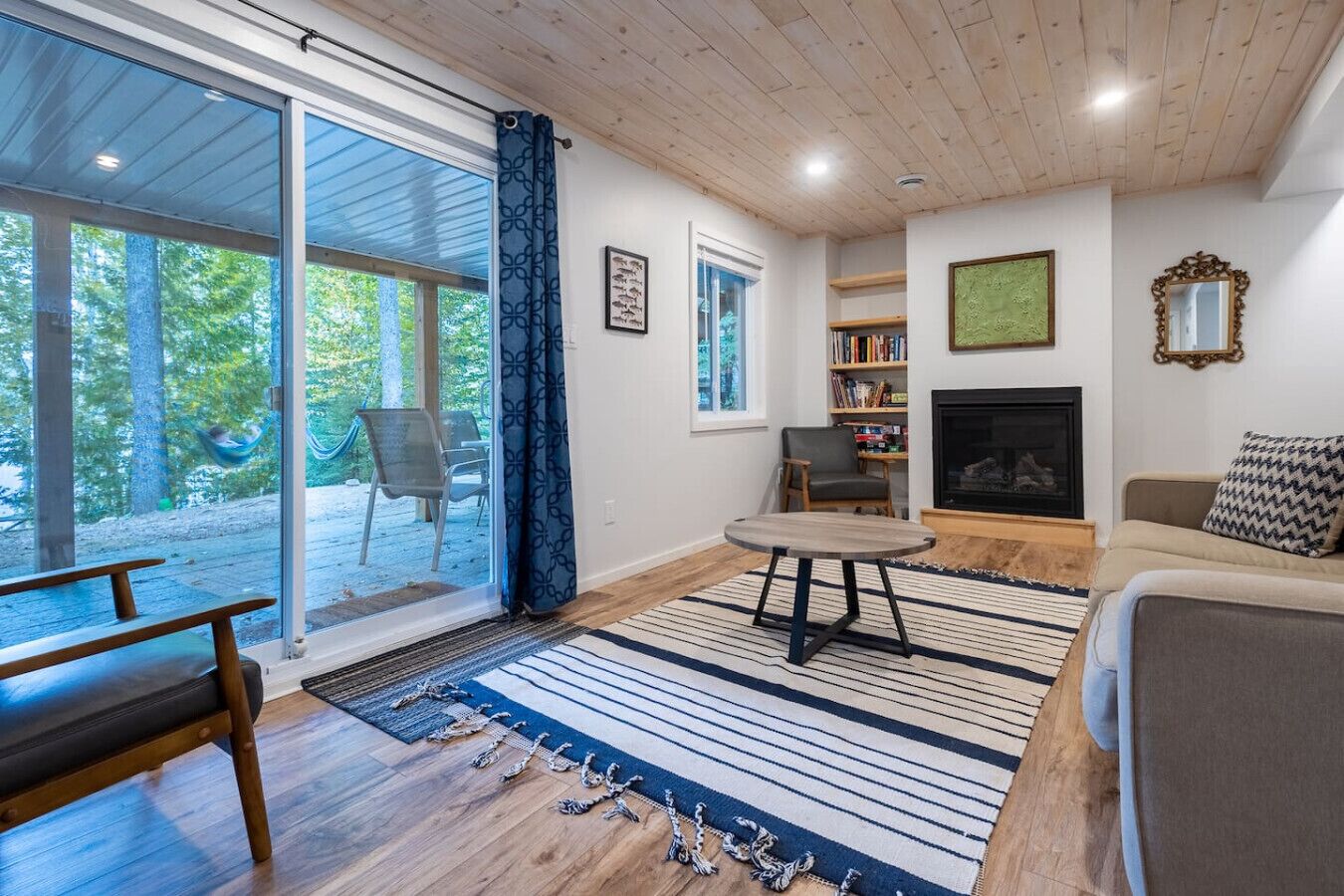 A living room with a fireplace, a sofa, a table, and a view of the outdoors.