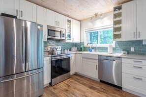 Una cocina moderna con electrodomésticos de acero inoxidable, armarios blancos y un ventanal que proporciona luz natural.