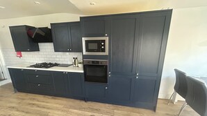 A modern kitchen with dark cabinetry, a microwave, an oven, and a gas stove. - 5BR Home w/ Parking for Groups & Contractors (Portsmouth)