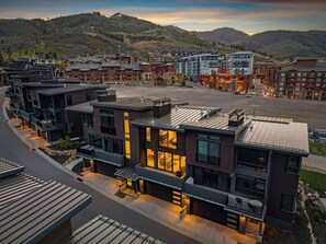 A modern hotel with a curved facade, large windows, and a parking area. - Ski-In 5BR Canyons Hideaway | Hot Tub, Ski Storage | Steps to Gondola (Park City)