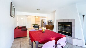 A dining area with a red table, chairs, and a fireplace. - Classy 70-ies style home with Mineralized Spa (Desert Hot Springs)