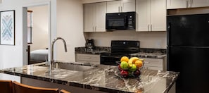 A modern kitchen with a marble countertop, a sink, a black refrigerator, and a microwave. - Winter Getaway Resort • 2BR Condo • Sleeps 6 • Jan 1–8 • On Golf Course (Scottsdale)