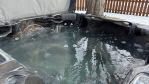 A hot tub with a tree and a wooden fence in the background.