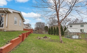 A residential area with a grassy yard, a wooden fence, a tree, and a greenhouse.