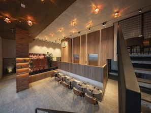 Eine moderne Hotellobby mit Empfangsschalter, Sitzgelegenheiten und einer Treppe.
