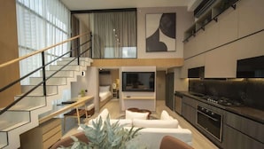 Een modern interieur met een trap, een zithoek met een bank en een eettafel, en een keuken met een kookplaat en kastjes.