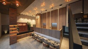Eine moderne Hotellobby mit Empfangsschalter, Sitzgelegenheiten und einer Treppe.