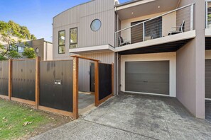 A modern two-story house with a garage, a balcony, and a fenced yard. - Spacious Townhouse Near Shops and Beach (Cowes)