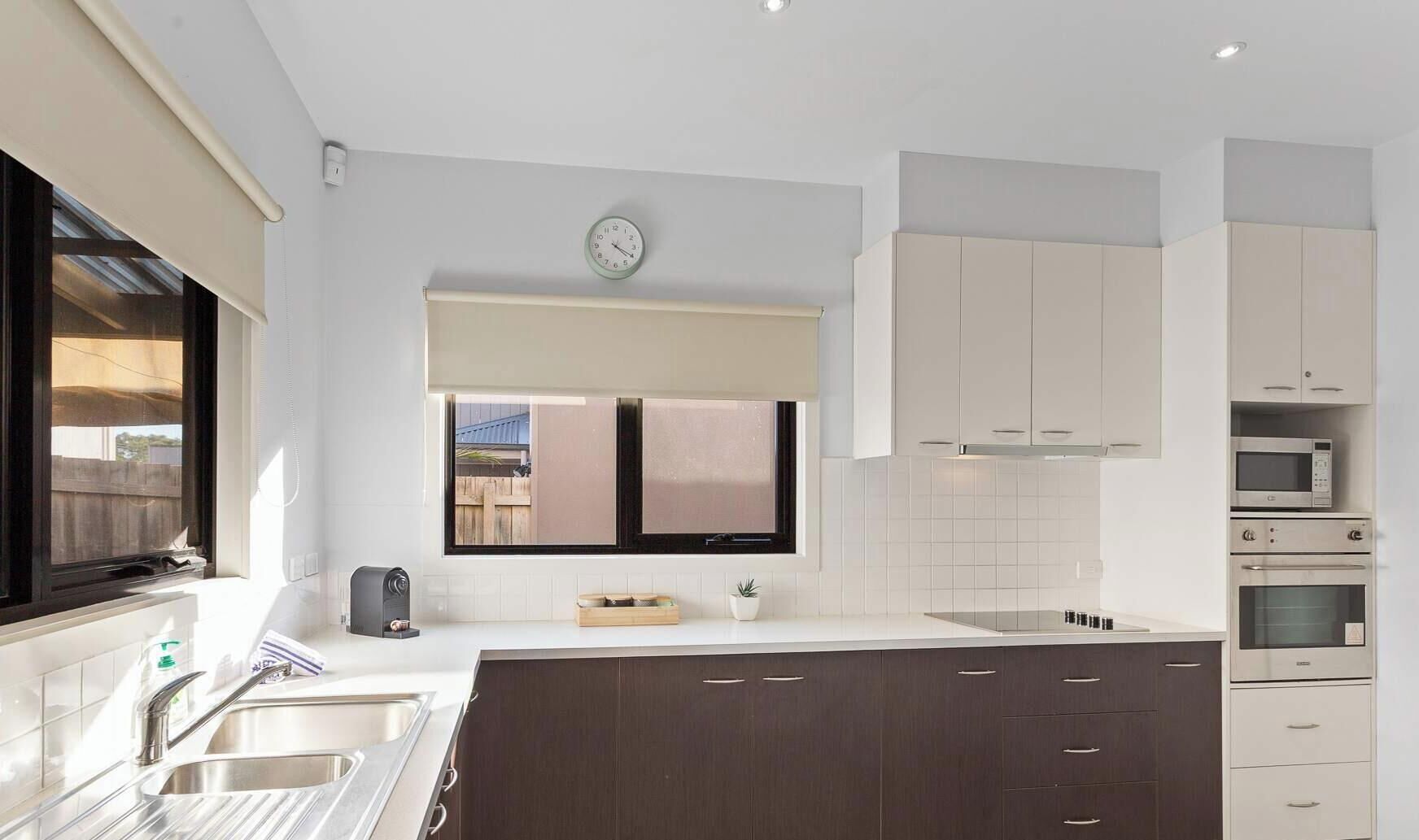 A modern kitchen with white cabinets, a built-in oven, and a window with a view.