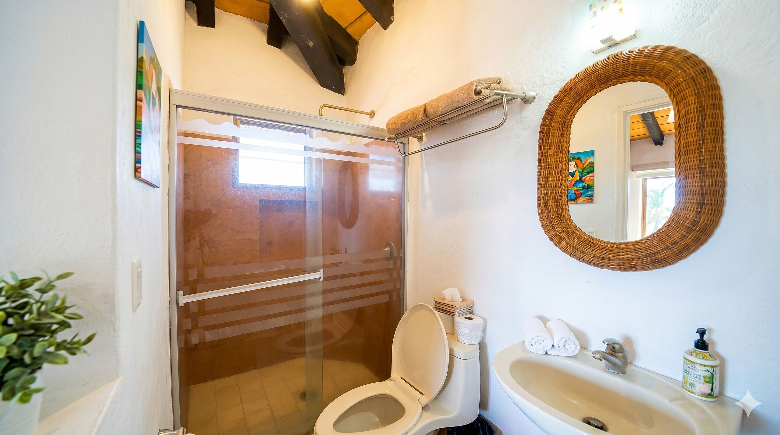 Une salle de bain avec une douche à porte en verre, des toilettes, un lavabo et un miroir.