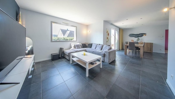 Ein modernes Wohnzimmer mit Sofa, Couchtisch und Fernseher.
