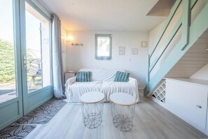 Ein Zimmer mit einem Bett, zwei runden Tischen, einem Fenster und einer Treppe.