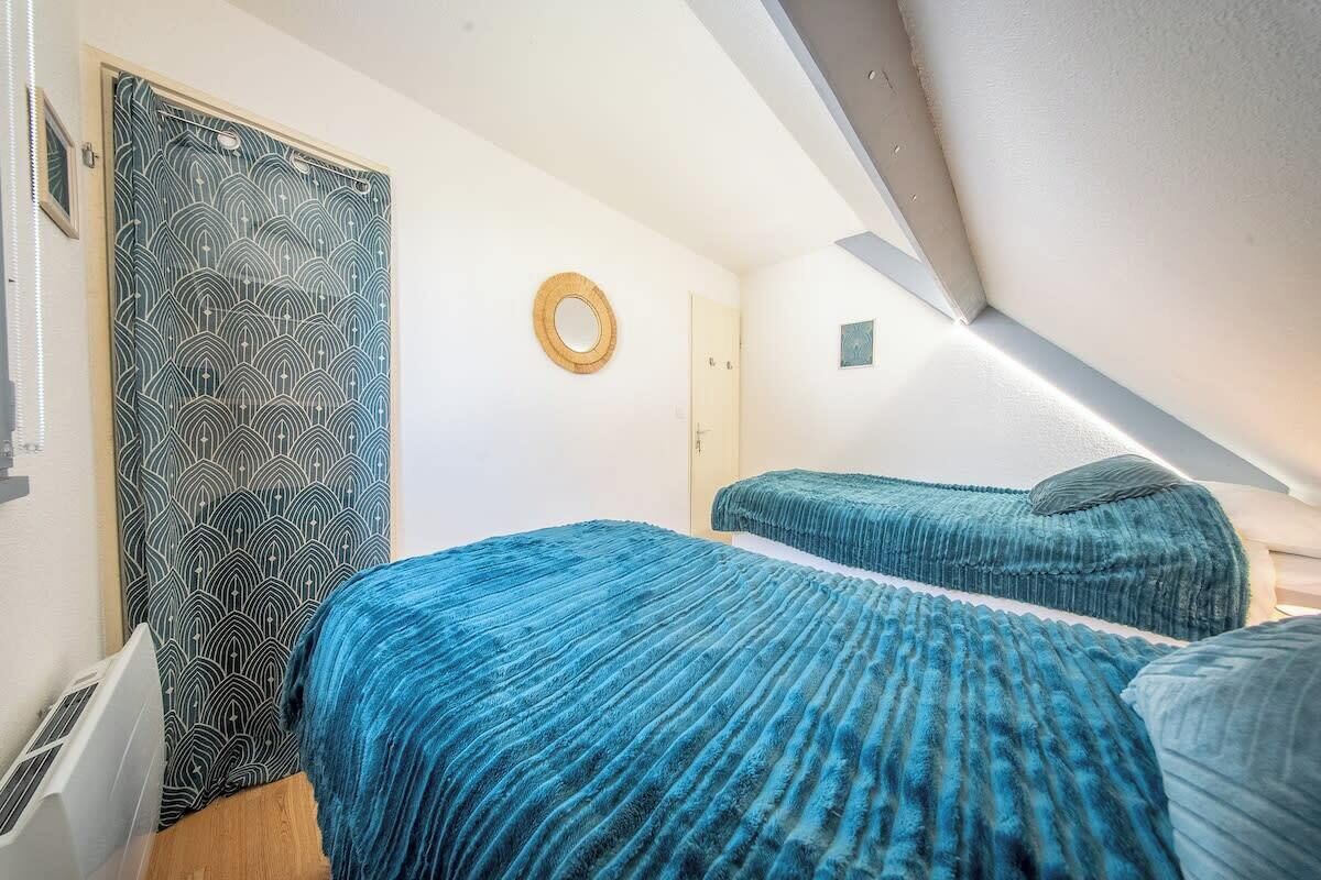 A small, modern room with two beds, a patterned door, and a circular wall decoration.